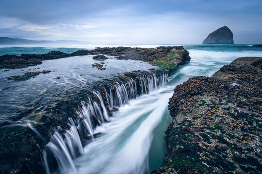Pacific Ocean washing over sandstone ledges with Chief Kiwanda Rock in the distance, Cape Kiwanda, Oregon, USA