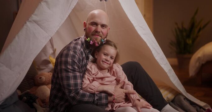 Warm hugs and playful laughter fill the air as a father and daughter create memories in their inviting indoor fort