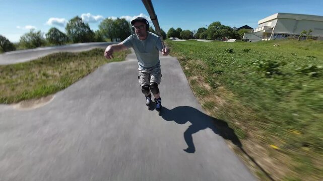 ​Athletic Adult Man Wearing Protective Gear and Helmet Enjoying Inline Skating and Rollerblading Action on a Sunny Asphalt Pump Track at Zabok, Croatia
