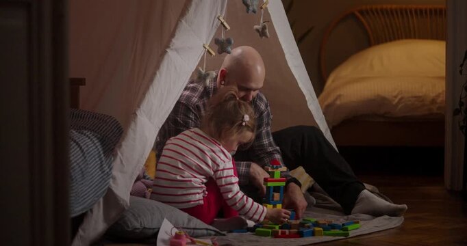 A grandparent and child share joyful moments building colorful structures inside a snug tent on a warm afternoon
