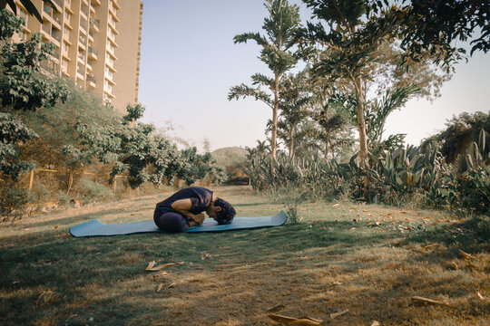 Woman Doing Baddha Konasana (Bound Angle Pose or Butterfly Pose) yoga in the garden. International Yoga Day