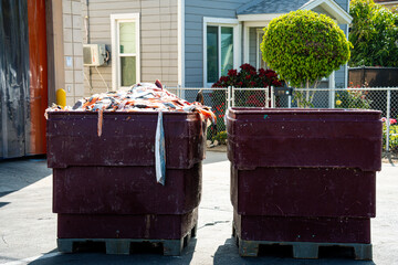 Large bins filled with fish waste sit outside a processing facility on a sunny day © Tom Harwood