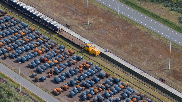 Aerial view of the Tata Steel industrial site featuring rows of steel coils and a yellow transport vehicle on tracks in Velsen-Noord, Noord-Holland, Netherlands.