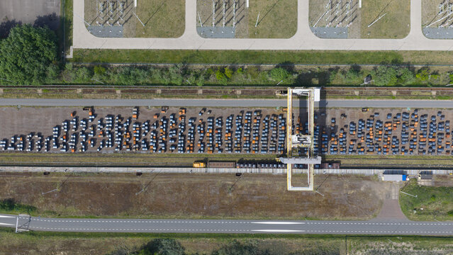 Aerial view of Tata Steel plant featuring rows of steel coils in a storage yard with a gantry crane and electrical infrastructure in Velsen-Noord, Noord-Holland, Netherlands.