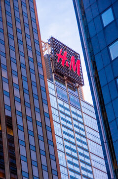 New York City, NY&mdash;June 16, 2018; An illuminated H&M billboard rises above modern skyscrapers in Midtown Manhattan surrounded by reflective office towers.