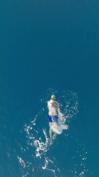 Man swimming backstroke style in ocean water blue summer sport overhead