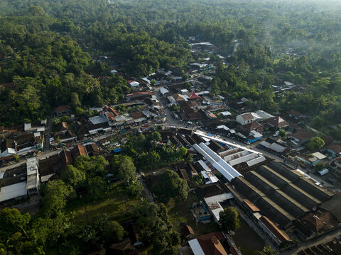 Aerial view of Pasar Kembang Klaten traditional market with its long industrial roofs surrounded by residential houses and lush tropical greenery Klaten, Central Java, Indonesia.
