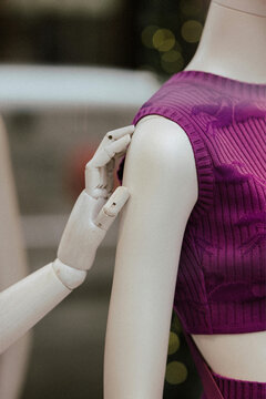 Tailor fitting purple dress on mannequin in atelier