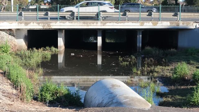 A concrete box culvert drainage system and a large pipe, under a suburban road with busy traffic in Melbourne, Australia. Concept of public works, municipal water and urban runoff management
