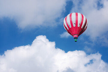 Fototapeta premium Red and white hot air balloon on the background of bright blue cloudy sky.
