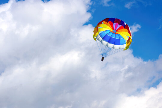 Paragliding using a parachute on background of blue cloudy sky.