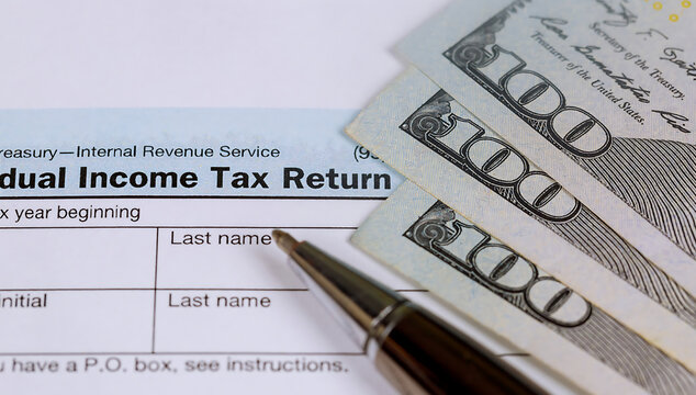Tax return form with pen and cash on top for payment