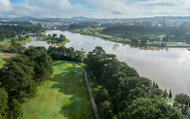 Fototapeta premium An aerial view of Xuan Huong Lake and the surrounding golf course in Da Lat, Vietnam, showcasing the city's natural beauty and recreational areas.
