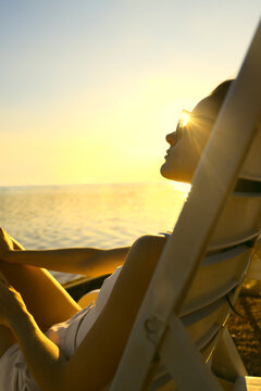 beautiful caucasian Woman at summer beach wear white swimwear swimming suit swimsuit lie on chaise deck lounge on blue water surface of sea river ocean pound aqua texture background backdrop. Sunset
