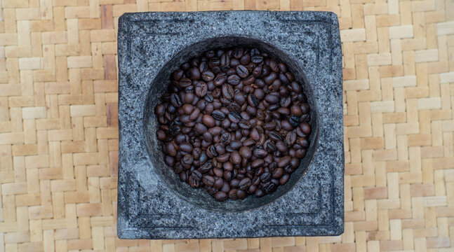 Roasted coffee beans in a mortar or grinding stone will be grounding manually