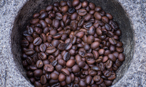 Roasted coffee beans in a mortar or grinding stone will be grounding manually