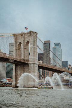 New York, USA, 2 May 2026: Portrait view of FDNY fireboat water display at Brooklyn Bridge. Vertical shot of fireboat spraying water jets in front of Brooklyn Bridge tower