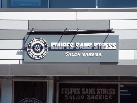Gatineau, Quebec, Canada &ndash; April 18, 2026: The "Coupes Sans Stress Salon Barbier" storefront features a gray sign with a circular logo and white 3D block lettering at  442 Boulevard Saint-Joseph.