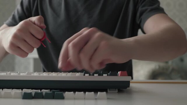 Enthusiast carefully removes keys. Closeup of the detailed hand movements during the key removal process. A calm workshop scene shows careful fingers removing keys from a home keyboard