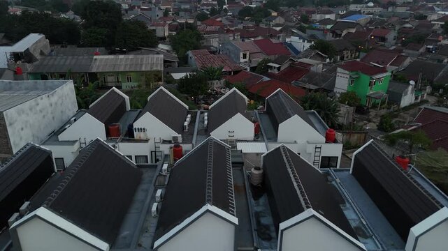 Aerial view of modern townhouse complex with uniform white triangular roofs in dense urban residential area of Jakarta