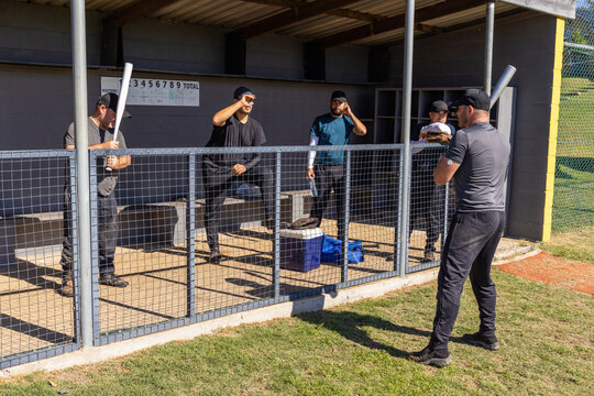 Five men preparing in baseball dugout, batter stepping up swinging bat updating animated scoreboard