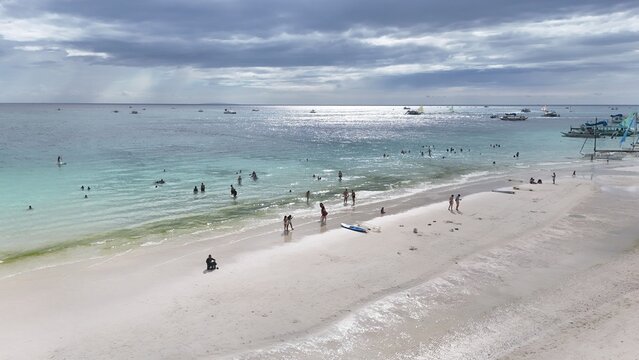 Malay, Philippines - 02 May 2026: Aerial view of Boracay Island with people on the white sand beach and turquoise water under a cloudy sky.