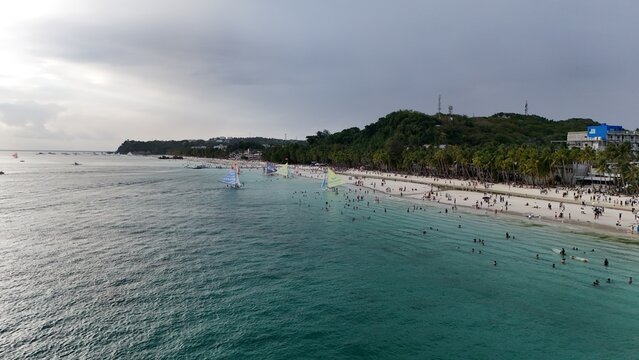 Malay, Philippines - 02 May 2026: Aerial view of Boracay Island with people swimming, sailboats on turquoise water, and palm trees along the white sand beach.