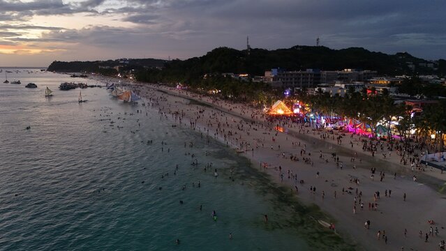 Malay, Philippines - 02 May 2026: Aerial view of Boracay Island's White Beach crowded with people at sunset, featuring sailboats on the water and illuminated resorts along the shore.
