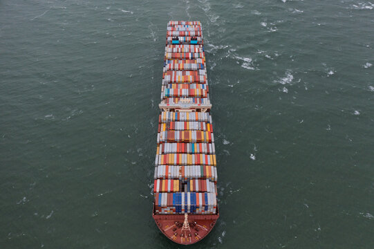 Antwerpen, Belgium - 05 September 2019: Aerial view of a massive container ship fully loaded with multi-colored cargo containers navigating through the open sea.