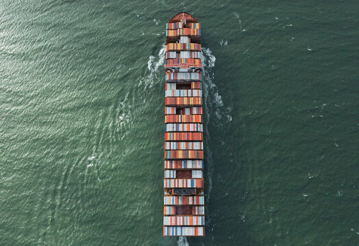Antwerpen, Belgium - 05 September 2019: Aerial view of a large container ship loaded with colorful cargo containers navigating through the green waters of the Port of Antwerp.