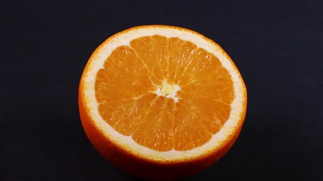 黒背景に映えるフレッシュなオレンジの断面の回転映像