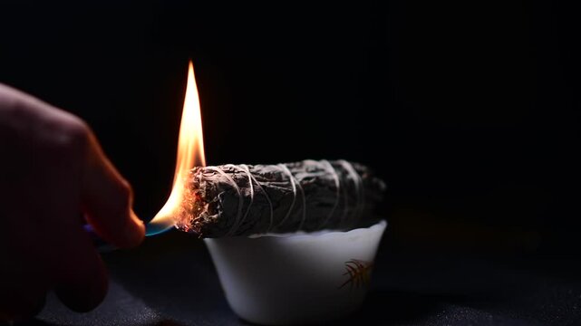 Sage lighter flame isolated sage flame smoke, dark background studio, ceremony spiritual practice theme, selective focus shadow depth of view 