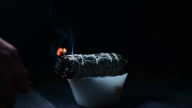 Sage lighter flame isolated sage flame smoke, dark background studio, ceremony spiritual practice theme, selective focus shadow depth of view 