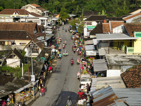 Klaten, Indonesia - 23 April 2026: Aerial view of Pasar Kembang Klaten traditional market with people on motorbikes and stalls along the street surrounded by rooftops and trees.