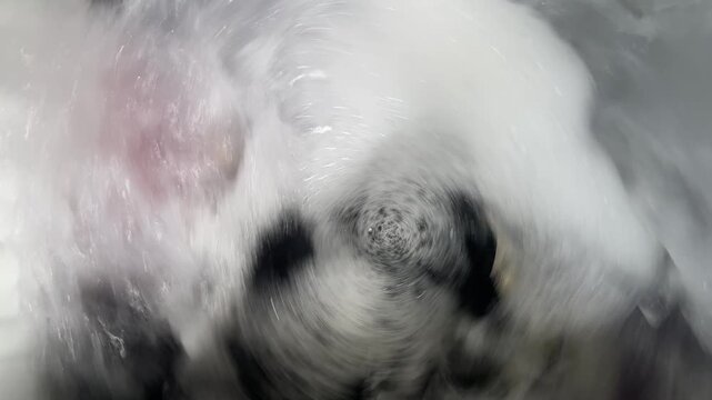 Laundry spinning in washing machine with soapy foam and bubbles