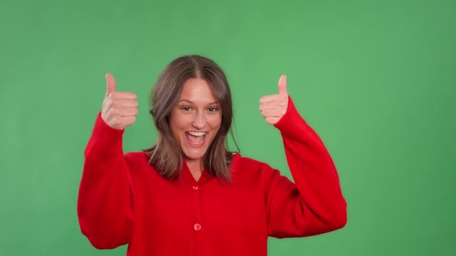 Happy woman gives thumbs up and celebrates in green screen studio