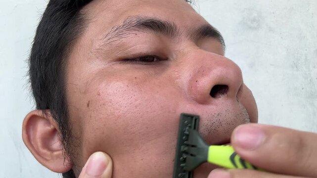 Close up of a man shaving his mustache with a manual razor