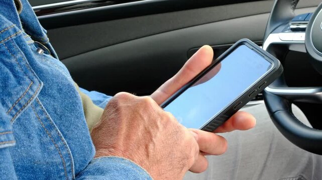 Man using smartphone inside car searching navigation route and travel information before road trip, mobile technology and transportation concept.