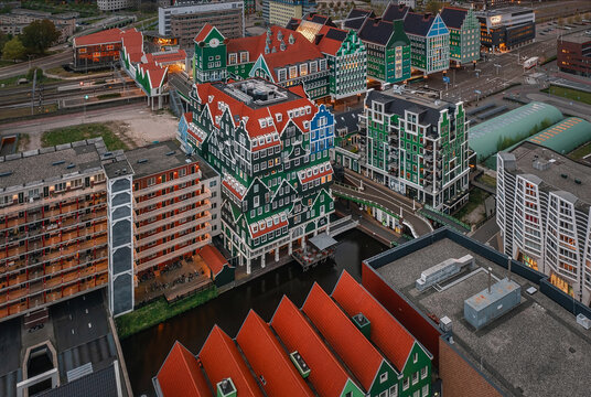 Zaandam, Netherlands - 26 April 2022: Aerial view of Inntel Hotels Amsterdam Zaandam featuring its iconic stacked green house facade overlooking the canal, railway tracks, and urban landscape.