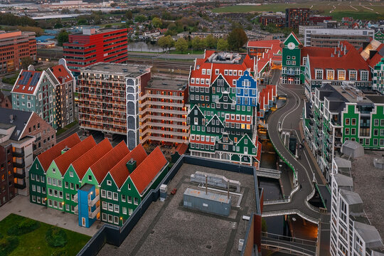 Zaandam, Netherlands - 26 April 2022: Aerial view of Inntel Hotels Amsterdam Zaandam with its unique stacked green house facade, surrounding urban architecture, and winding waterways at dusk.