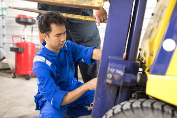  Two men inspect a forklift in a warehouse. One points at the machine's structure. The other observes closely, holding a clipboard. They appear focused and professional © bank