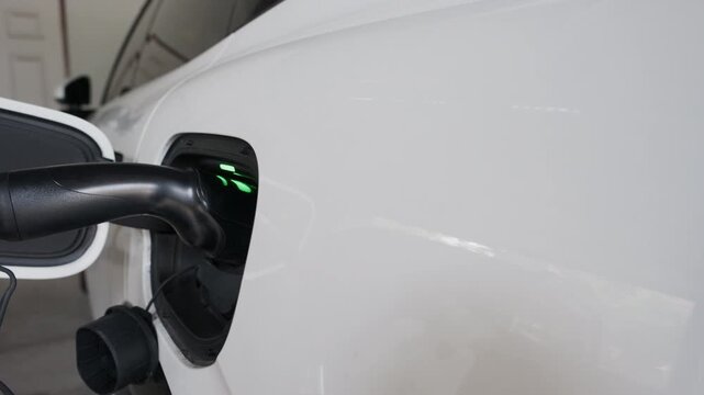 4K slow motion person charging electric car at home.	
