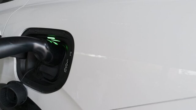 4K slow motion person charging electric car at home.	
