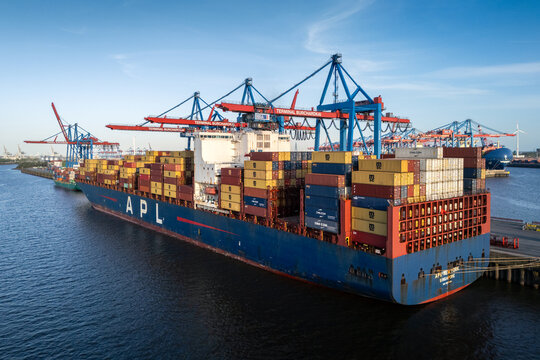 Hamburg, Germany - 26 April 2026: Aerial view of HHLA Container Terminal Burchardkai with a large APL container ship docked under massive gantry cranes in the port of Hamburg.