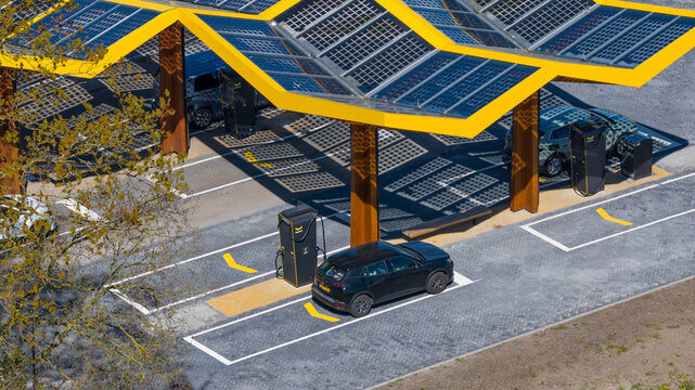 Bant, Netherlands - 21 April 2026: Aerial view of the Fastned charging station with its iconic yellow solar roof and electric cars parked at charging points.