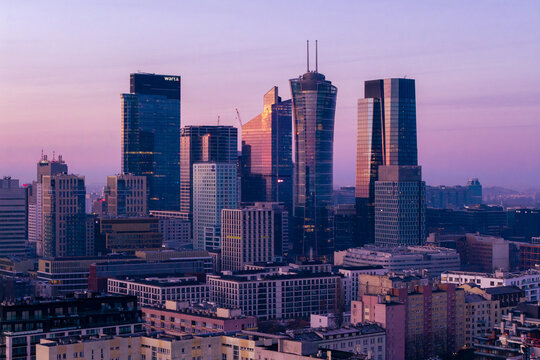 Warsaw, Poland - 06 March 2026: Aerial view of the modern skyline with skyscrapers including Spire Tower under a purple sunset sky.