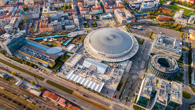 Cheskomoravska, Czechia - 21 April 2026: Aerial view of the O2 arena and surrounding modern urban architecture with residential buildings and streets under clear daylight.