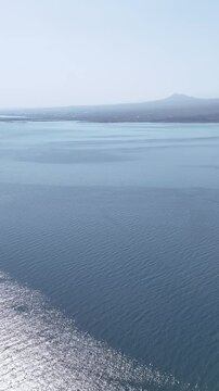 Vertical drone view of Lake Sevan with misty hills on the horizon, Armenia