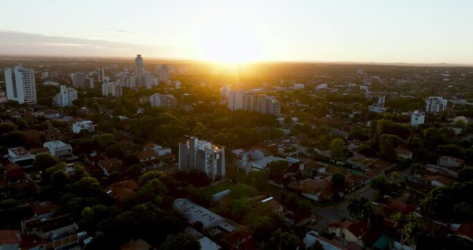 Aerial view of Asuncion at sunset with sun flare over skyline and residential neighborhoods. Captures warm light, urban development, and atmosphere in Paraguay&rsquo;s capital.