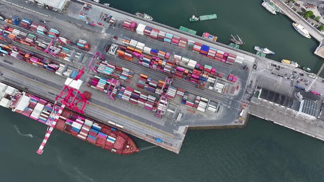 High above a busy cargo port, ships arrive and depart, loading and unloading colorful shipping containers.